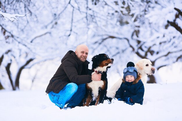 The beautiful father, son and dogs sitting on the snow