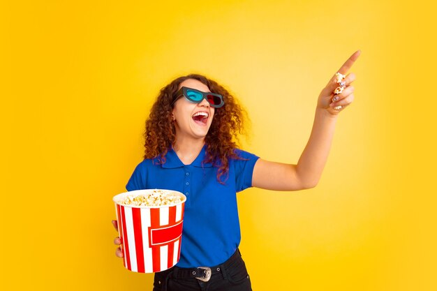 Beautiful female curly model in shirt pointing with popcorn