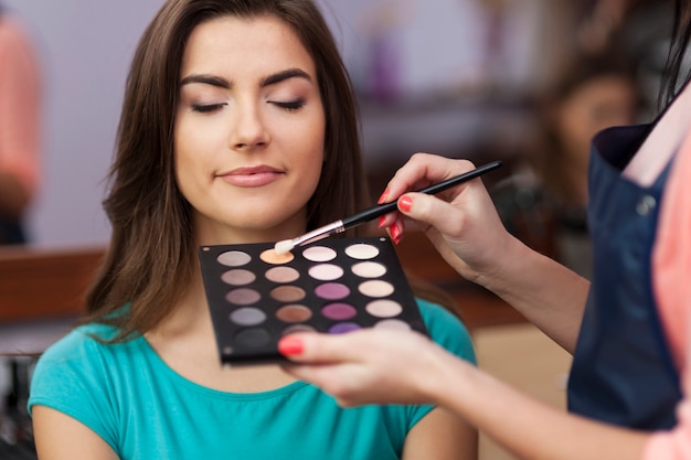 Beautiful female customer during the work of makeup artist