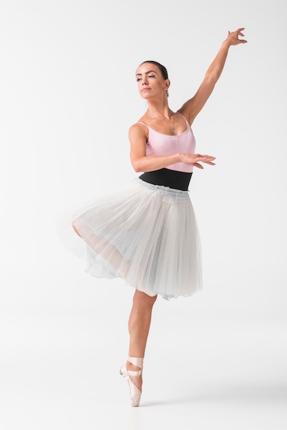 Beautiful female dancer in elegant white tutu against white backdrop