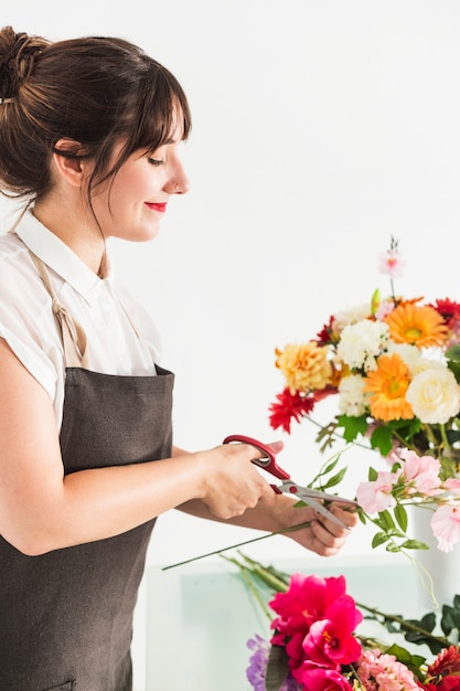 Beautiful female florist cutting flower stem with scissors