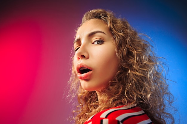 Beautiful female half-length front portrait on red and blue background.