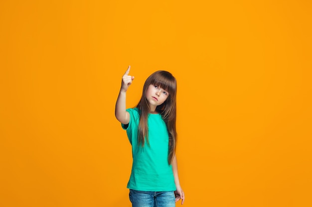 Beautiful female half-length portrait on orange studio backgroud. The young emotional teen girl