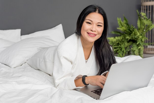 Beautiful female laid in bed with laptop