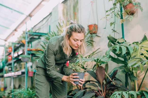 Free photo beautiful female nursery worker working in greenhouse