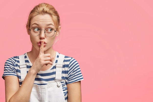 Free Photo beautiful female student keeps fore finger in hush gesture