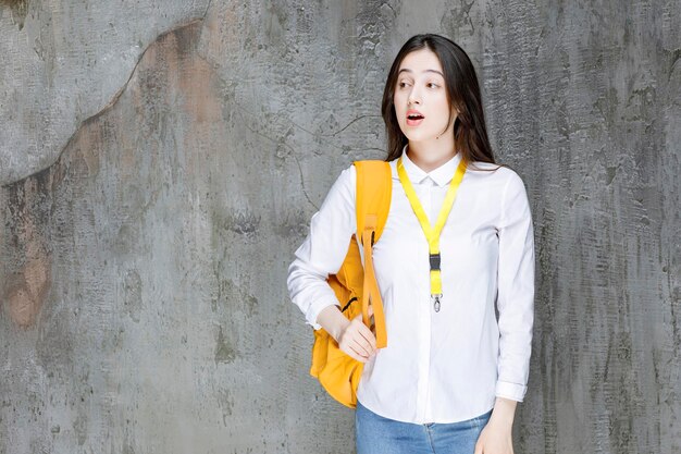 Beautiful female student with yellow backpack standing. High quality photo