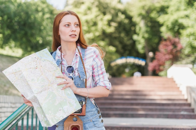 Beautiful female with map in park