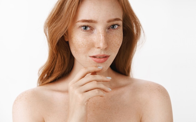 Free photo beautiful feminine and attractive woman with natural red hair and freckles on face and body touching chin gently with fingers and gazing sensual and relaxed taking care of beauty and skin