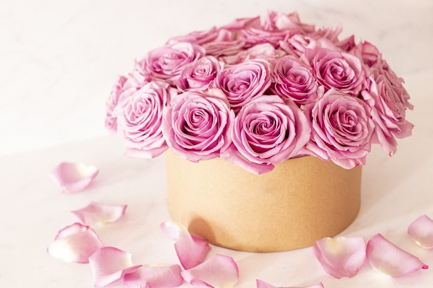 Beautiful floral bouquet with pink roses in a box on a pink background