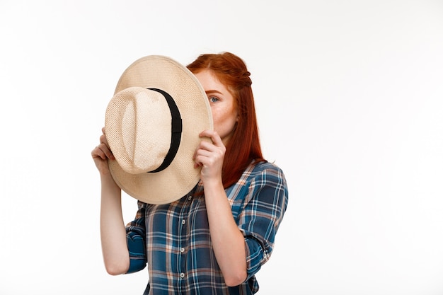 beautiful ginger girl with hat over white wall.