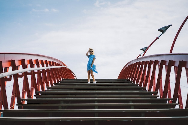 Free photo beautiful girl in a blue dress posing on the bridge