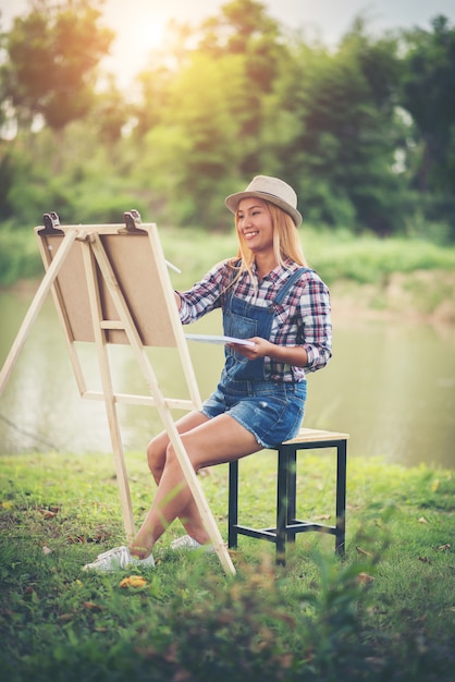 Beautiful girl draws a picture in the park