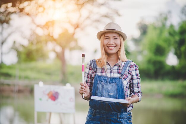 Beautiful girl draws a picture in the park