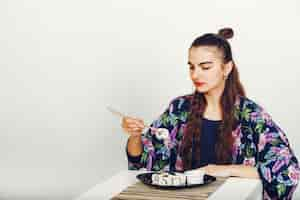 Free photo beautiful girl eating a sushi in a studio