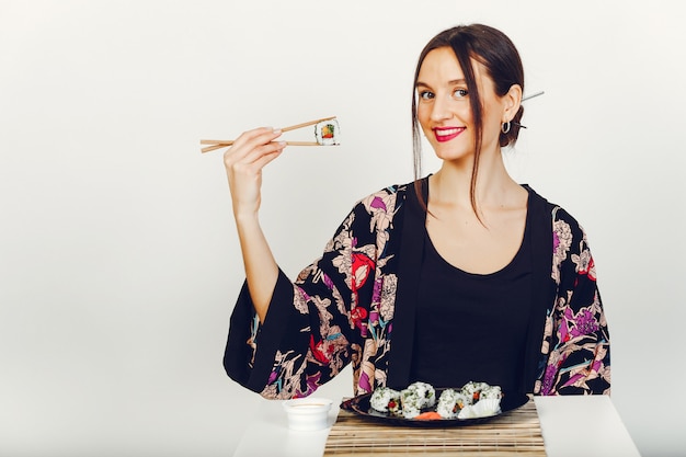 Free Photo beautiful girl eating a sushi in a studio