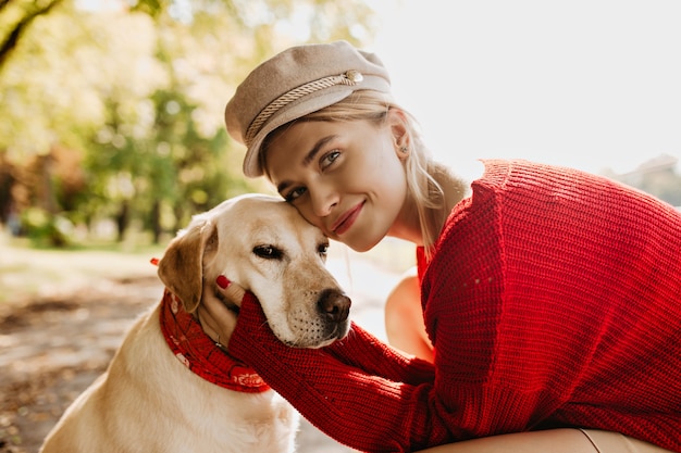 Beautiful girl and her dog together with love. Charming blonde woman with her pet enjoying sunny autumn day.