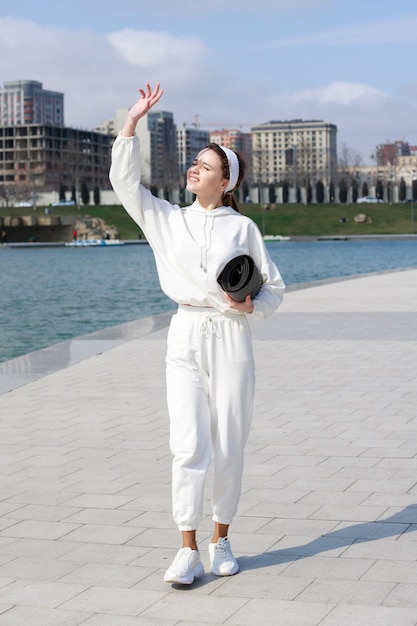 Beautiful girl holding her mat and closing sun with her hand High quality photo