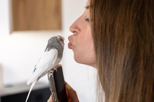 Free Photo a beautiful girl holds a parrot on her hand and kisses it