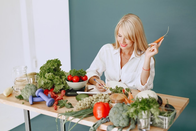 Free photo beautiful girl make a salad. sporty blonde in a kitchen. woman writing recipe in notebook.