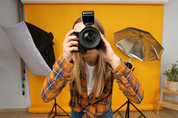 Free photo beautiful girl photographer in the photo studio on a yellow background