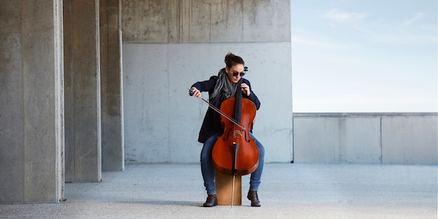 Free Photo beautiful girl plays the cello with passion in a concrete environment