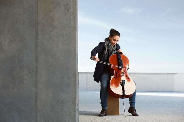 Free Photo beautiful girl plays the cello with passion in a concrete environment