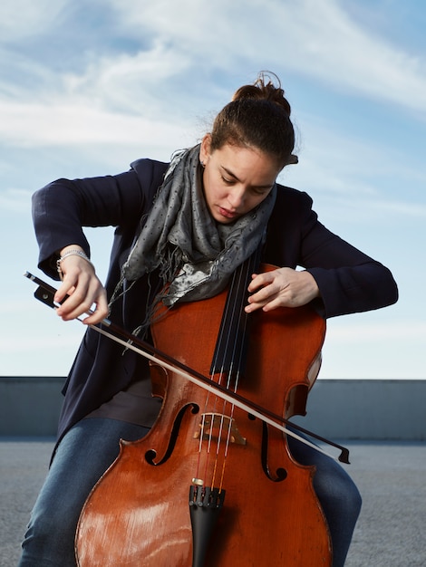 Free Photo beautiful girl plays the cello with passion in a concrete environment