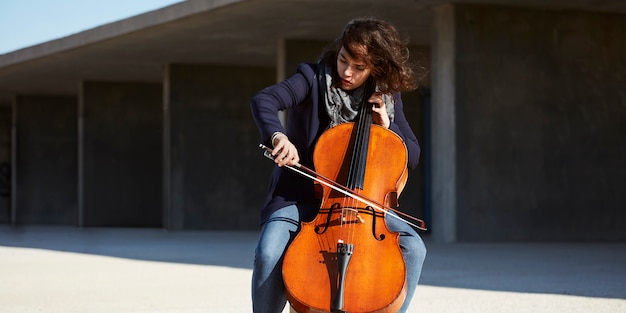 Free Photo beautiful girl plays the cello with passion in a concrete environment