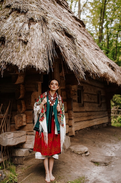 Beautiful girl poses on the courtyards near the house in a traditional Ukrainian dress