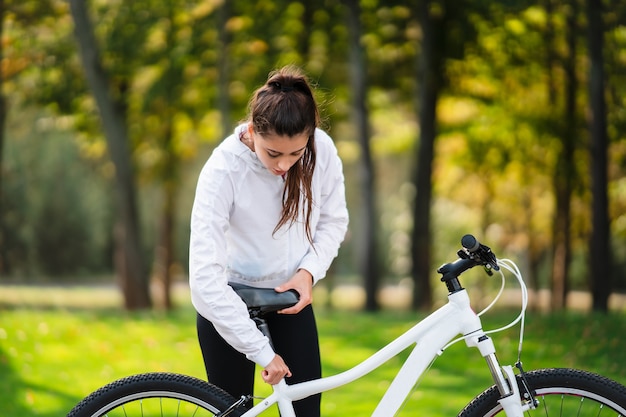 Beautiful girl posing at white bicycle. Walk in nature.