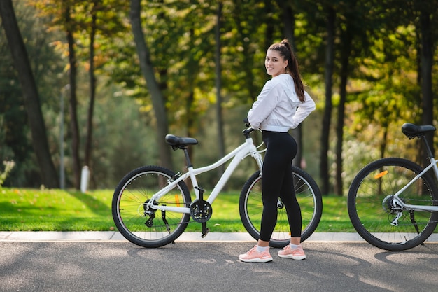 Beautiful girl posing at white bicycle. Walk in nature.