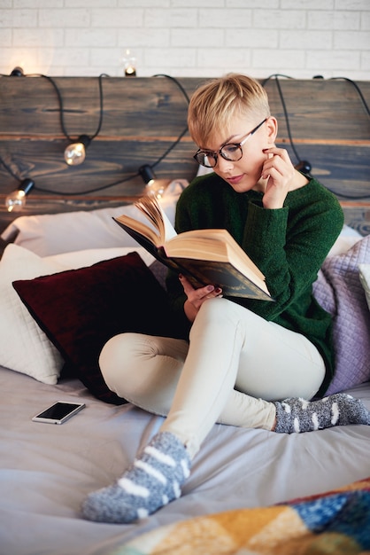 Free photo beautiful girl reading a book in bed