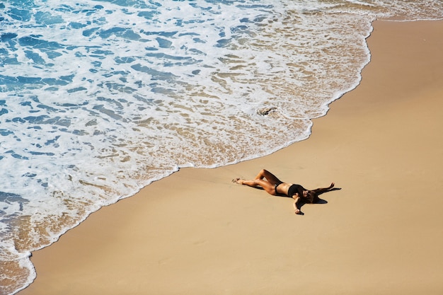 Beautiful girl relaxing on the wild beach. amazing view from the top.