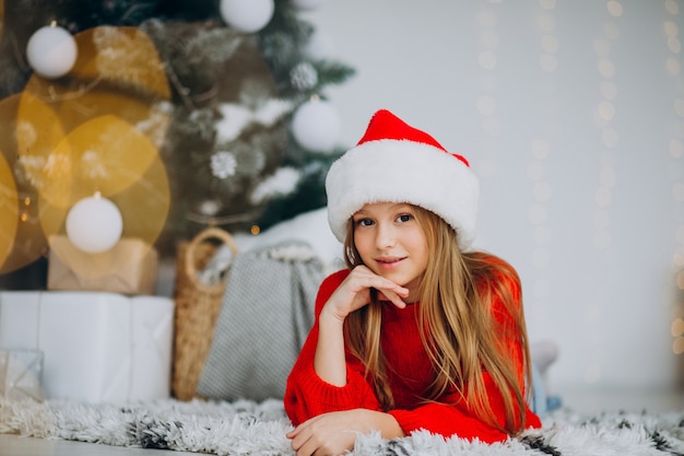 Beautiful girl in santa hat under the christmas tree