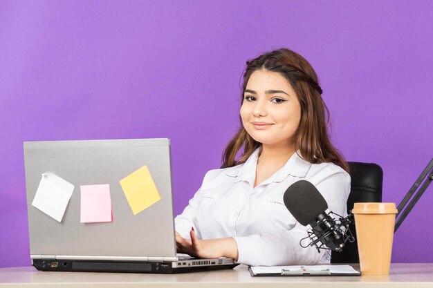 Beautiful girl sittin behind desk and smiling to the camera High quality photo