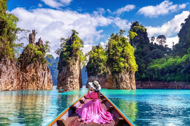 Free photo beautiful girl sitting on the boat and looking to mountains in ratchaprapha dam at khao sok national park, surat thani province, thailand.