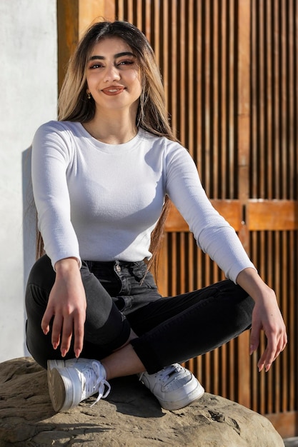 A beautiful girl sitting on the rock and smiling High quality photo