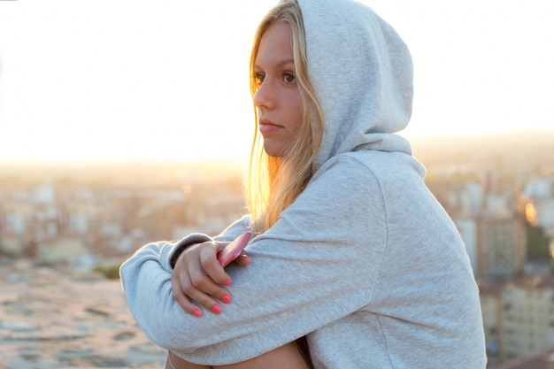 Beautiful girl sitting on the roof and listening to music.