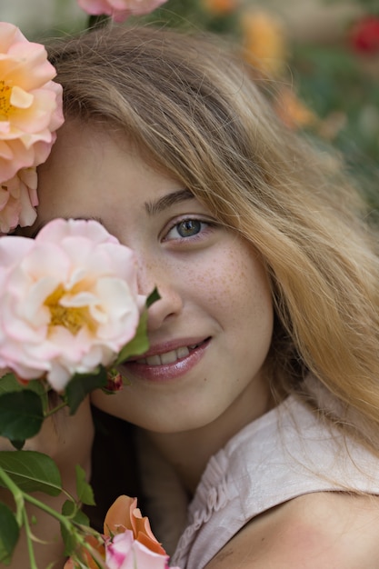 Free photo beautiful girl sitting and smiling near the flowers, outside during daytime.