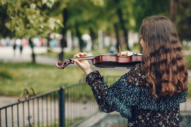 Beautiful girl in a summer park with a violin