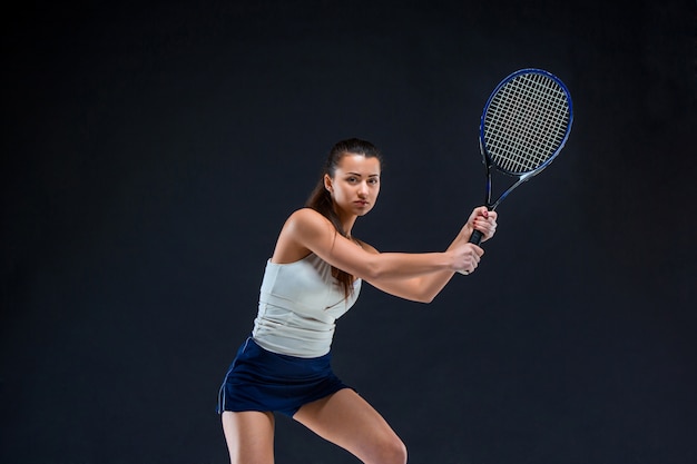 beautiful girl tennis player with a racket on dark background