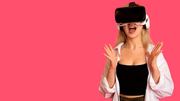 Beautiful girl in VR glasses on a pink background in virtual reality