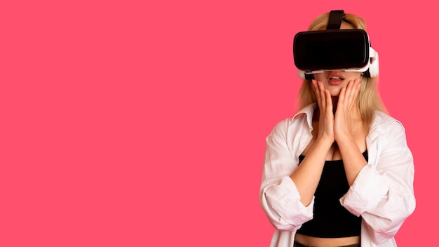 Beautiful girl in VR glasses on a pink background in virtual reality