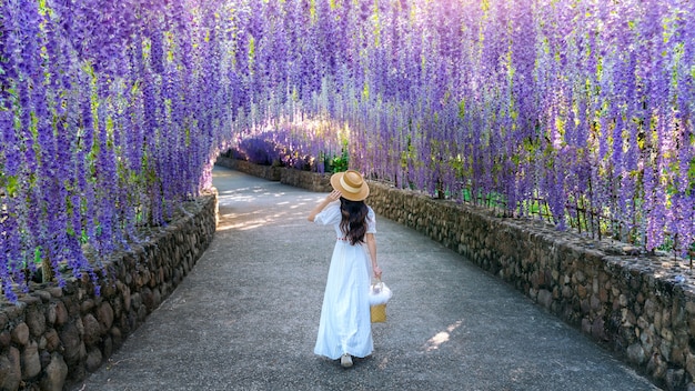 Free photo beautiful girl walking at purple flower tunnel in chiang rai, thailand