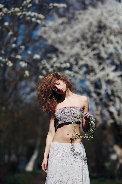 Free photo beautiful girl walks in the lush garden dressed in a wreath