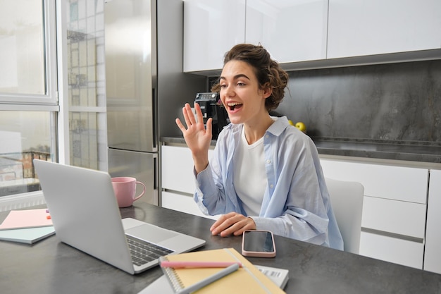 Free Photo beautiful girl waves hands at laptop camera says hello to coworkers connects to work meeting online