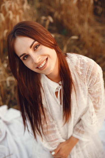 Beautiful girl in a white dress. Woman in a autumn wheat field.