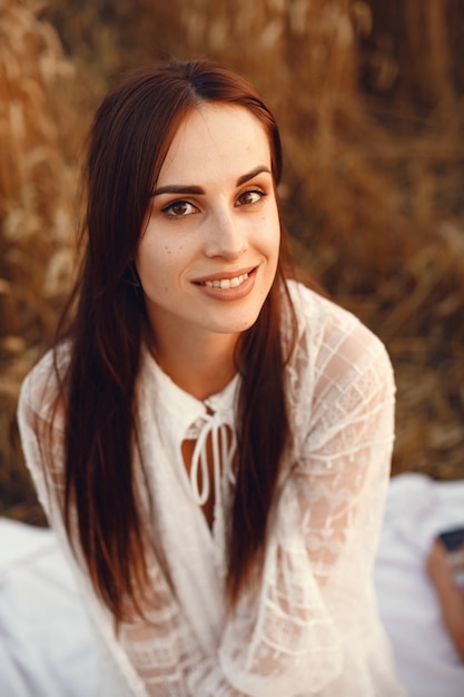 Beautiful girl in a white dress. Woman in a autumn wheat field.