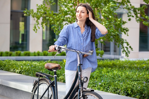 Beautiful girl with a bicycle on the road